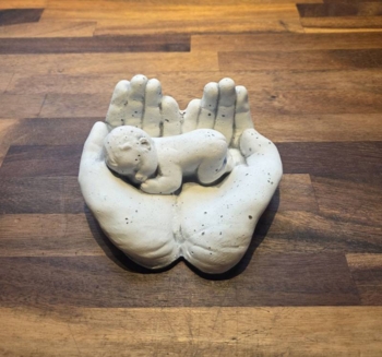 Hænder med baby i hvid cement