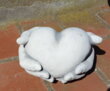 Hånd holder/giver hjerte i hvid beton